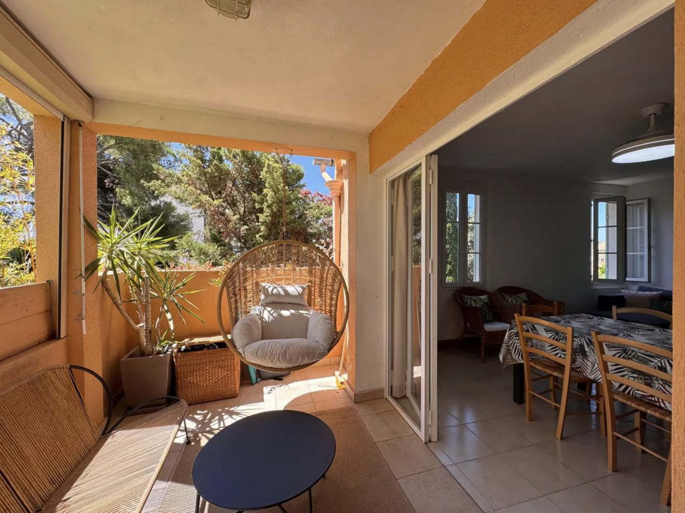 Terrasse couverte avec fauteuil suspendu ouverte sur la salle à manger, maison gérée par BOLIEUX à Bandol