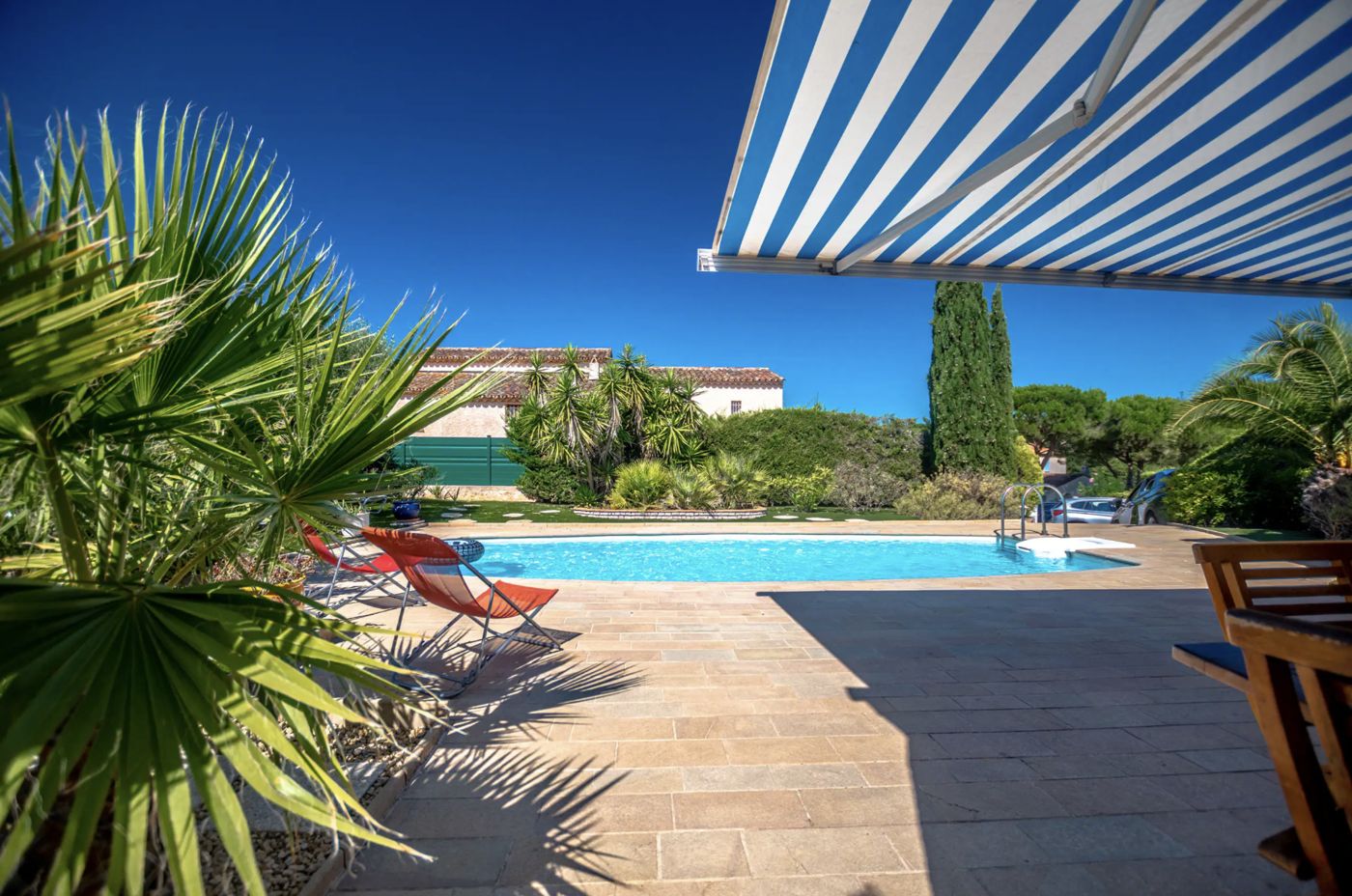 Piscine de la villa vue depuis la terrasse sous le store rayé